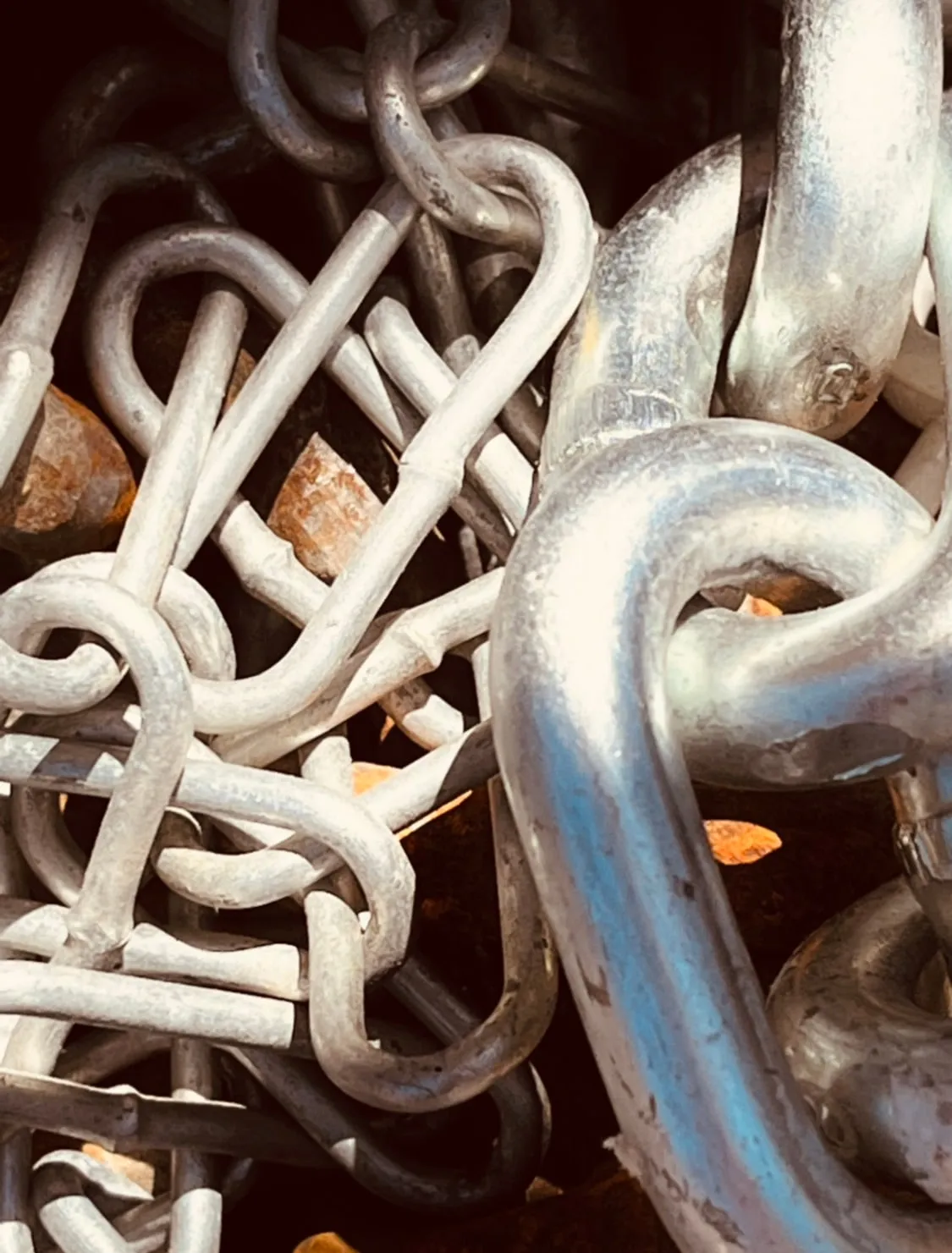 Close detail of galvanised chain and rigging hardware in a jobsite bin.